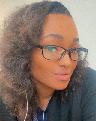 Headshot of a woman with black glasses, light skinned tone and wavy light brown hair.