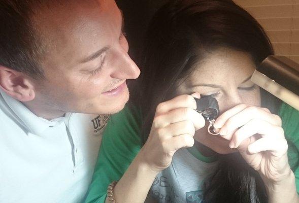 Newly engaged couple examining their ring while having it appraised for insurance coverage.