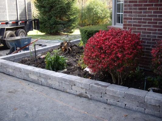 Finishing the shrub bed after the sidewalk and retaining wall have been completed for Shelby Township home