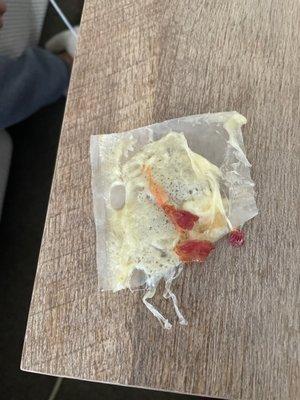 Plastic cheese wrapper with cheese and bacon pulled out of the wrap.