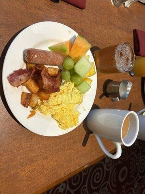 Scrambled eggs, Sausage, fruit, breakfast potatoes, and bacon