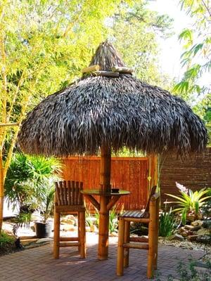 Bamboo tiki umbrella and bar stools with palm thatch roof