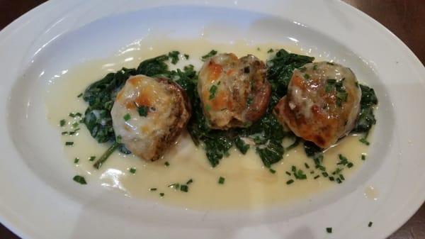 Stuffed mushrooms atop fresh spinach in a savory light cream sauce