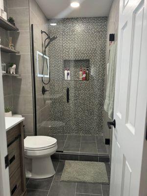 Guest bathroom renovation that boasts a beautiful glass tile accent wall that reflects the perfect amount of light