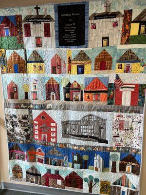 Quilt with buildings including the library featured.