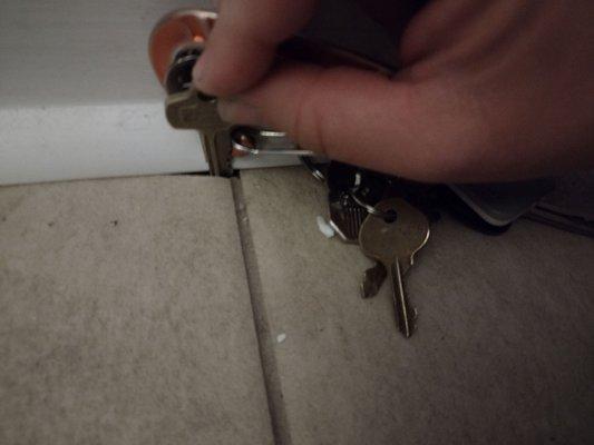 Jagged edges of broken tile peek out from under quarterround. I put my keys in the hole to show that it's a hole.