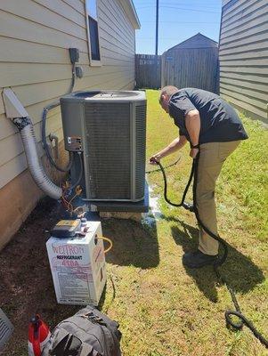 Billy is cleaning the Condenser coils of debris such as dust,grass,bugs and other particulates and charging the system with freon.