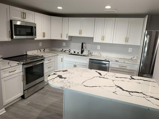 Expanded white shaker kitchen by replacing the wall with eat on island. Doubled the drawers & usable quartz counter space.