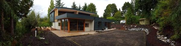 A new construction with raingarden, cedar raised beds, irrigation lines, a patio that runs the length of the house, and tiered pathways