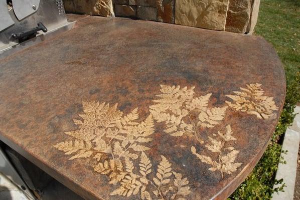 Inlaid fern on stained concrete. Perfect as part of the grill.