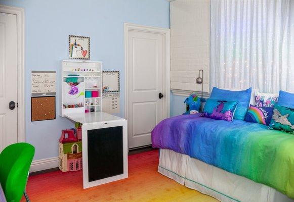 This client wanted a Rainbow Unicorn Room!  LED rainbow lights are behind a white sequin curtain at the bed. The murphy table is for art!