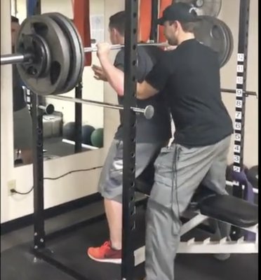 Strength Coach Andrew Spotting a Lakeville South football player doing a 445lb. Bench Back Squat for Advantaged Strength Development.