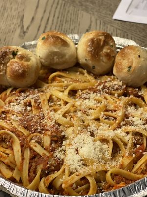 Fettuccine Bolognese with a side of garlic knots bread.