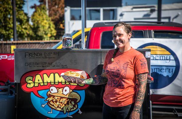 Chef/Owner Sam holding signature cheesesteak in front of Sammies food cart!