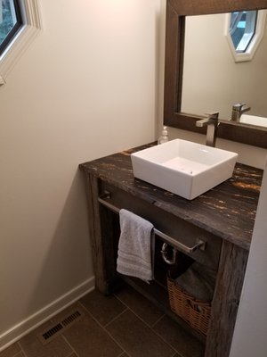 Bathroom remodel with upgraded cabinetry to re claimed lumber cabinet and matching mirror. The tile floor was existing and was steamed clean