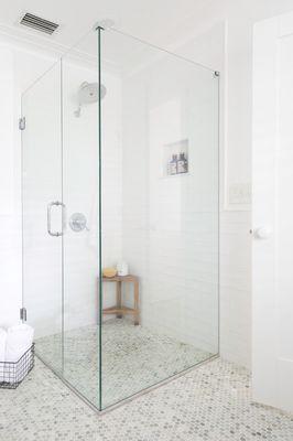 Custom built curb less shower, with light green marble penny tiles subway tile walls and frameless glass shower enclosure