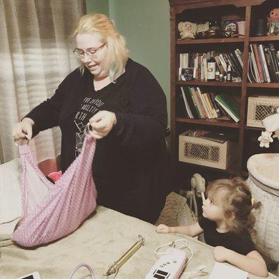 Midwife Kristy Hammack weighing a brand new baby, closely supervised by big sister.