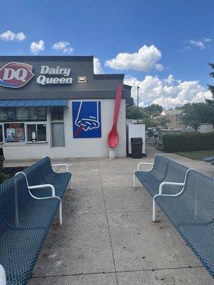 Outdoor seating in shade and sun, with spoon sculpture