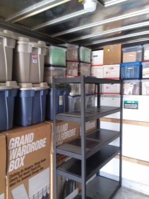 The inside of a truck being loaded with boxes,crates and Shelf's.