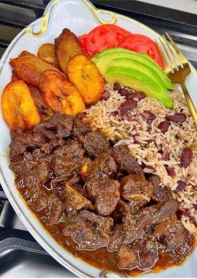 Brown Stew ( Chicken, Beef or Lamb ) marinated in a savory sauce with peas and rice , plantain and side salad.