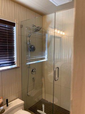 A recent shower enclosure hung over ceramic tile.