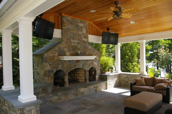 Inside view of an outdoor living area with masonry chimney, distressed wood ceiling, Azek trim work and metal seem roof.