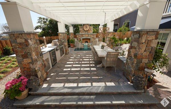 Outdoor kitchen and living area remodel. Featuring a custom BBQ grill and kitchen set up, al fresco dining area, paver patio and fireplace.