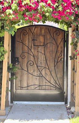 One side of a pair of incredibly designed gates, complete with chestnut stained wood and metal vine overlay, expertly crafted by our welders