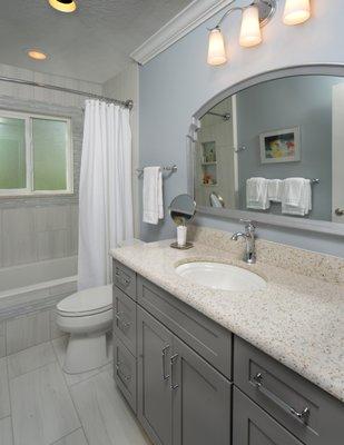 This small guest bath features a custom tiled bath skirt coordinating decorative wall tiles, /the counter is quartz speckled with sea glass.