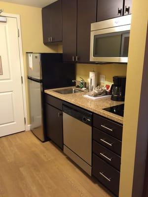 Very nice kitchenette that is stocked with dishes, pots and pans, and flatware.