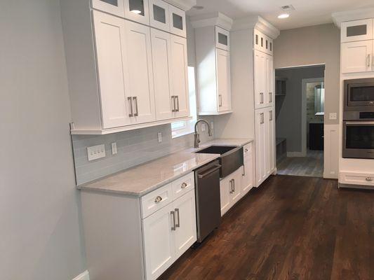 White shaker cabinet. White carrera marble countertop with stainless steel farm sink.