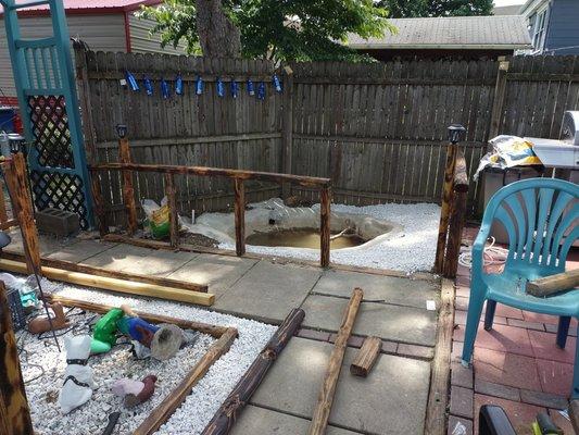 Cement pond with burnt landscaping timber railing and white crystal rock's