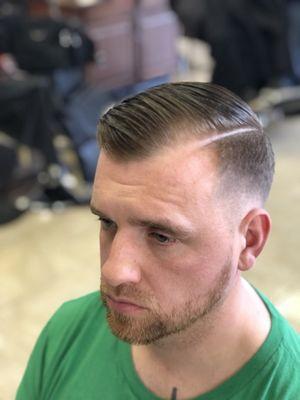 Combover with a low skin fade and a nice clean hard part together with the beard line up !!