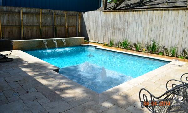 Geometric swimming pool with tanning ledge, bubblers, water scuppers and extended travertine deck. Peak Pools and Spas