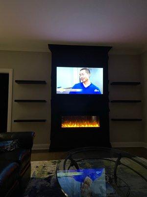 Feature wall with floating shelves and electric fireplace.