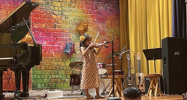 A child performs her violin recital at the Encore Spring Costume Concert