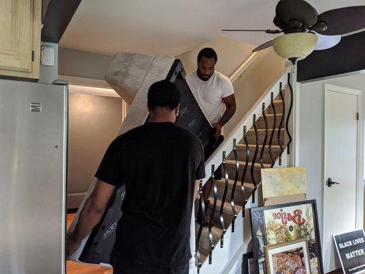 Movers helping a client move a tricky couch upstairs