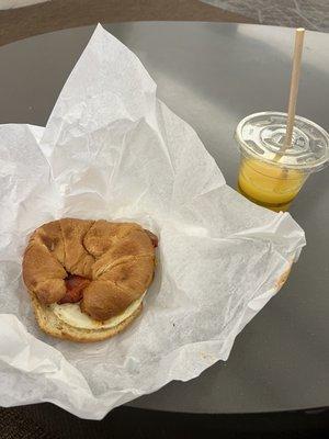 Bacon, egg, and cheese on a croissant, with an orange juice