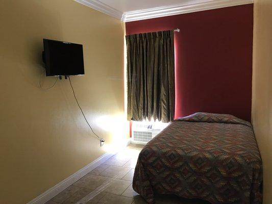 Hotel bedroom with A/C unit and 32" T.V.