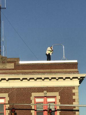 It appears this man may be installing a new blue light for emergencies on the roof of the fire department