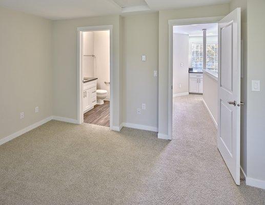 Apartment bedroom with beige carpets and light colored walls.