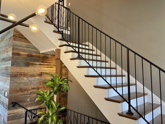 Custom stair railing fabricated with 1/2 inch round mild steel balusters embossed with a tree bark pattern.  Cast iron shoes on all 1" posts