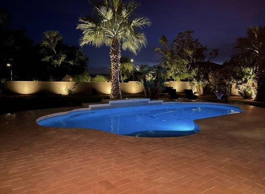 Travertine patio extension with landscape accent lights throughout the yard.