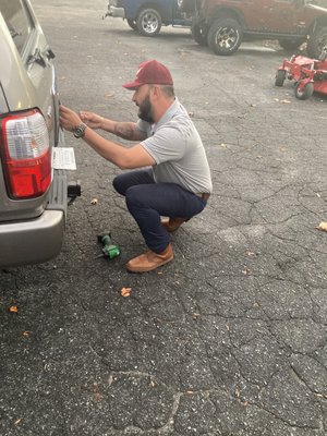 Multi-tasker Israel Rodriquez putting my license plate upon my recently-purchased Toyota Four-Runner Limited SUV.