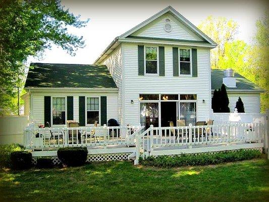 Our back deck with tables and chairs, a grill and shade umbrellas.