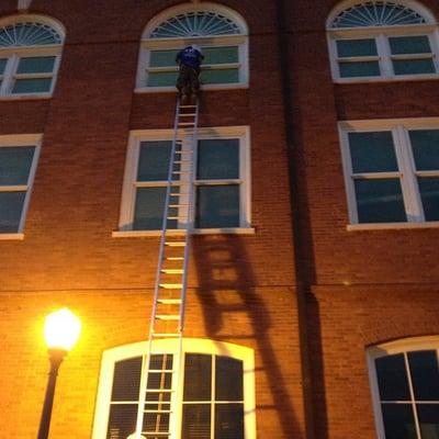 A VIP Special Services Window Cleaner working late atop a 48' ladder at Clemson University in Clemson, SC.