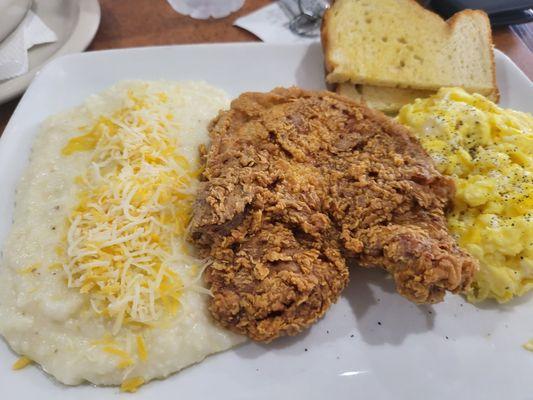 Grits with cheese, fried pork chop, scrambled eggs,  and toast