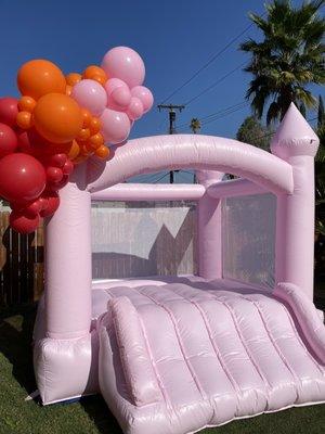 Pink Bounce House rental with small balloon garland