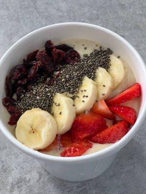 Decadent oatmeal bowl topped with fruits, chia seeds, and dried cranberries.