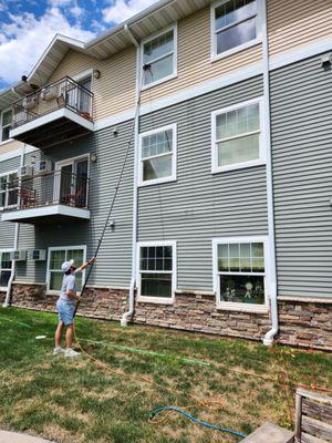 Nico using water fed pole to clean apartment windows.